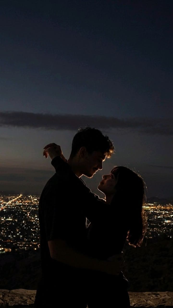 A couple embracing above city lights after dark